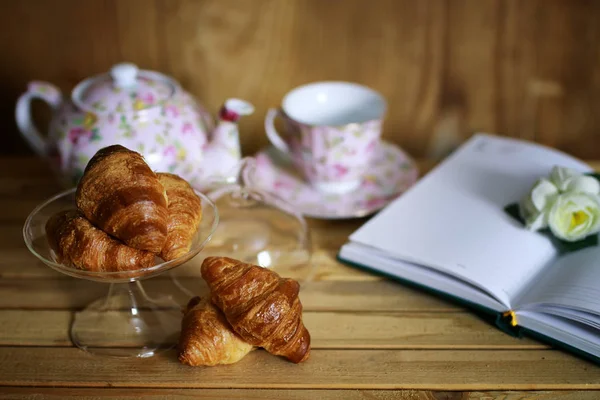 Tasse mit Tee Croissant Buch — Stockfoto