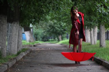 kadın bir yağmurluk ve şemsiye