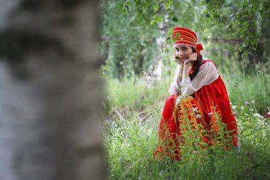 Geleneksel elbiseyle Slav doğada oturuyor