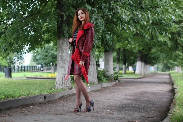 Frau mit rotem Regenschirm an Straßenbaum — Stockfoto