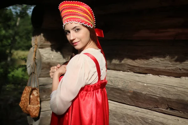 Dziewczyna w tradycyjnym stroju drewniane ściany — Zdjęcie stockowe