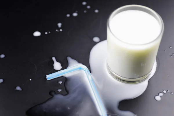 Glass of milk splashing and tube straw on table — Stock Photo, Image