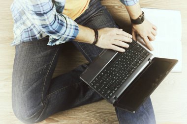 Yerde dizüstü bilgisayarı olan bir adam var.