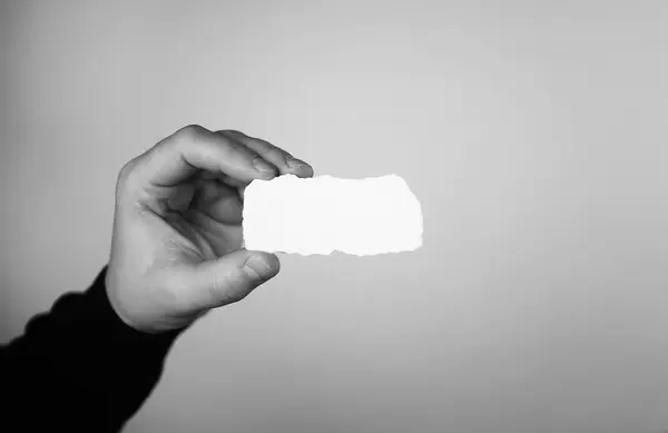Kis fehér darab papír a kezében ember monokróm — Stock Fotó