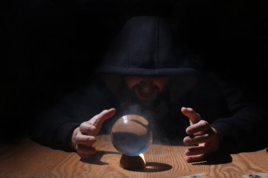 adam siyah başlıklı cristal topu ile