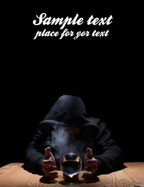 Man in a black hood with cristal ball and empty space for text — Stock Photo, Image