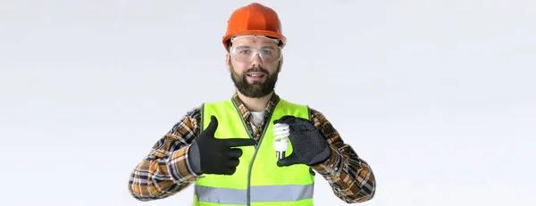 Travailleur dans un casque et des vêtements de protection avec une ampoule dans — Photo