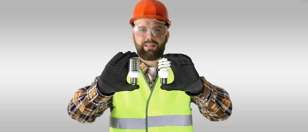 Dělník v přilbu a ochranné oděvy s žárovky — Stock fotografie
