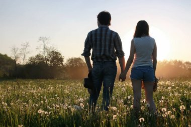 Bahar akşamında gün batımında yürüyen iki genç insan.