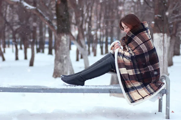 Bella ragazza con i capelli lunghi avvolti in una coperta seduta su un ben — Foto Stock