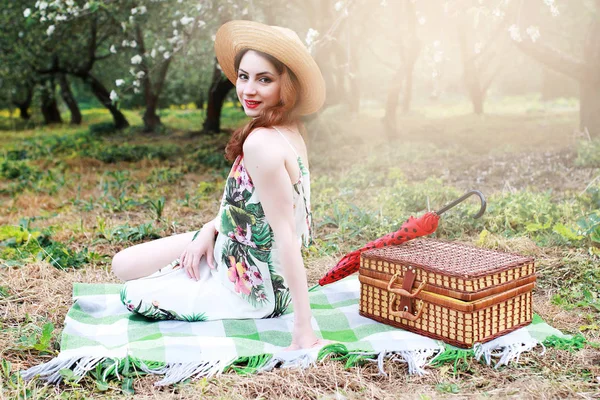 Девушка на пикнике в яблоневом саду с корзиной продуктов — стоковое фото