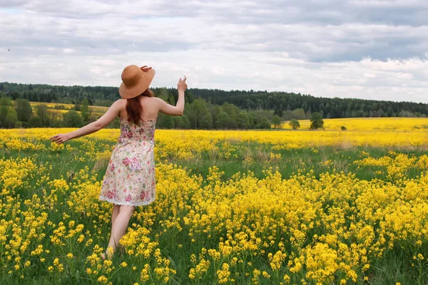 Fille dans un champ de fleurs avec panier et un chapeau — Photo