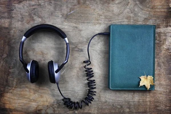 Auriculares audiolibros y libro sobre mesa de madera — Foto de Stock