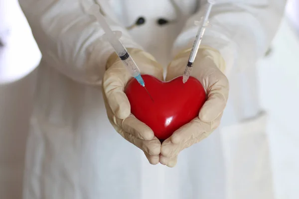 syringe in heart doctor hand