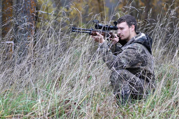 Homem em camuflagem e com armas em um cinto florestal em um hun primavera — Fotografia de Stock