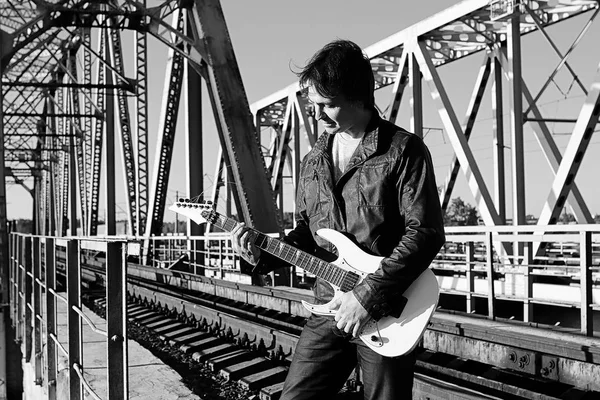Černobílý muž s elektrickou kytaru v průmyslové landsca — Stock fotografie