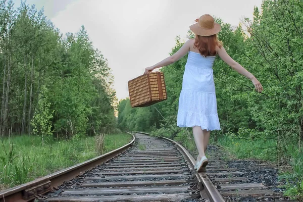 Flicka i en vit solklänning och korg resväska promenader på räls — Stockfoto