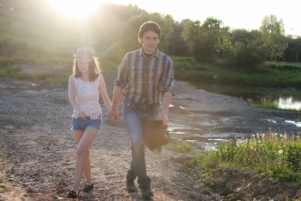 Couple de jeunes marchant au coucher du soleil soirée de printemps dans un — Photo