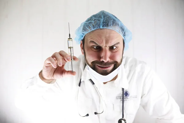 Божевільний бородатий лікар у білому пальто та старому шприці — стокове фото