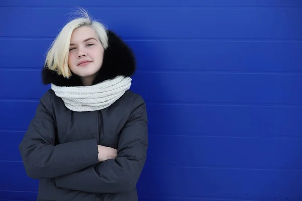 Junges schönes Mädchen auf einem Winterspaziergang an der blauen Wand — Stockfoto