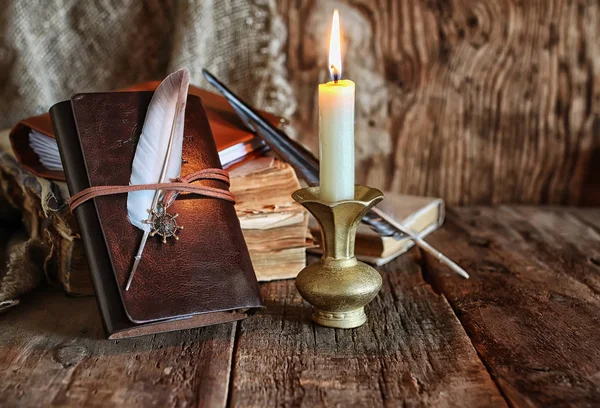 Feder und Buchroman in der Nähe der Kerze — Stockfoto