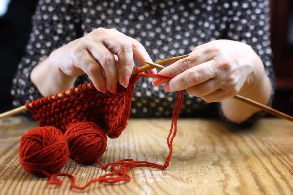Bejaarde vrouw houdt zich bezig met het breien van warme truien voor haar grand — Stockfoto