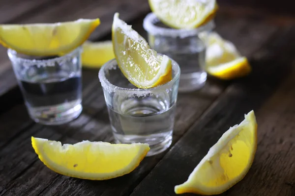 Pilha de tequila com sal e limão em um fundo de madeira — Fotografia de Stock