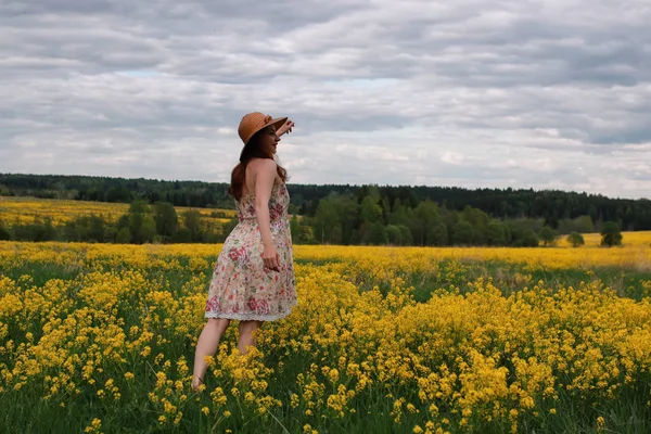 Menina em um campo de flores com cesta e um chapéu — Fotografia de Stock