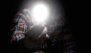 Adam elinde parlayan lambayı tutuyor.