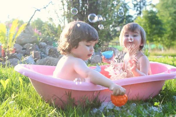 Ikrek fiú és lány fürdővíz szabadban — Stock Fotó