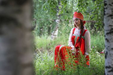 Geleneksel elbiseyle Slav doğada oturuyor