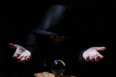 adam siyah başlıklı cristal topu ile