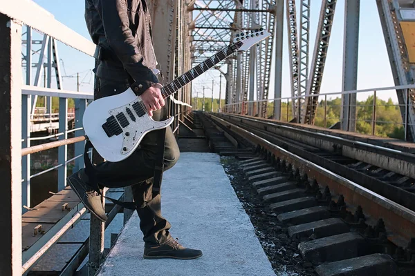 Homem com uma guitarra elétrica na paisagem industrial ao ar livre — Fotografia de Stock