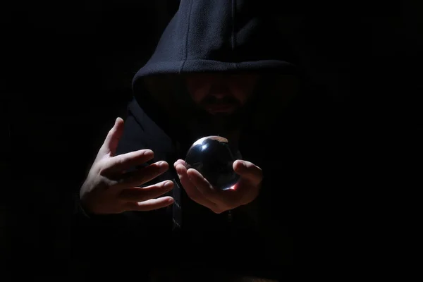 Man in een zwarte kap met cristal bal — Stockfoto