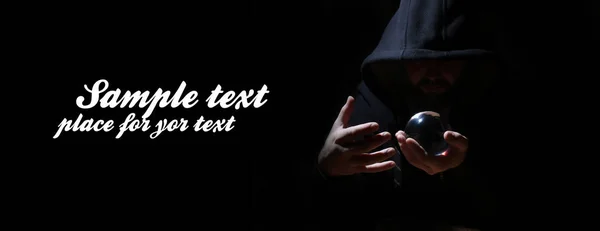 man in a black hood with cristal ball and empty space for text