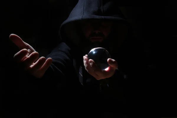 Man in een zwarte kap met cristal bal — Stockfoto