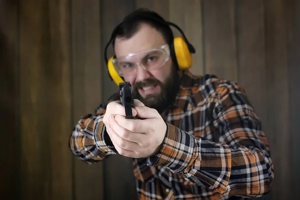 Людина з одягненими захисними окулярами і навчанням вуха в пістолеті ш — стокове фото