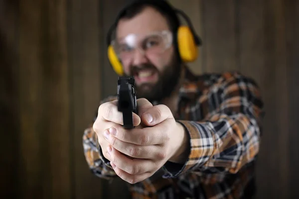 Homem com colocar em óculos de proteção e treinamento de orelha em pistola sh — Fotografia de Stock