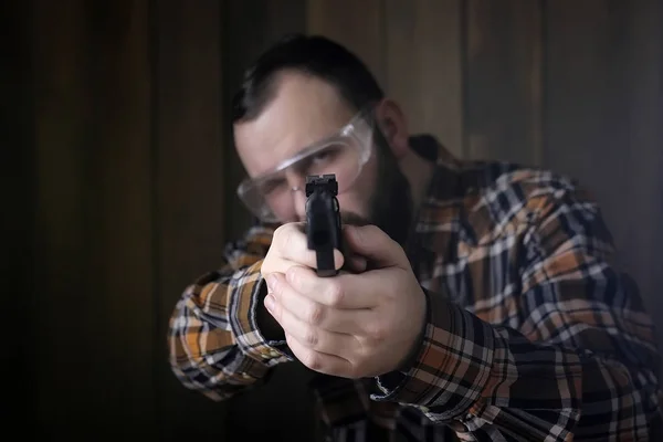 Homem com colocar em óculos de proteção e treinamento de orelha em pistola sh — Fotografia de Stock