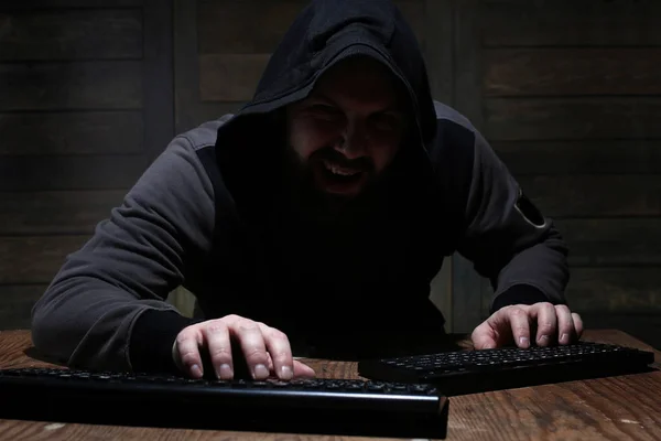 hacker in the black hood in a room with wooden walls