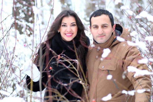 Belo jovem casal em um parque nevado envolto — Fotografia de Stock