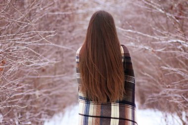 Kışın bir battaniyeye sarılmış mavi gözlü kız