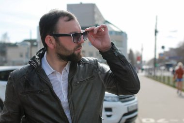 Ceketli ve güneş gözlüklü sakallı adam.