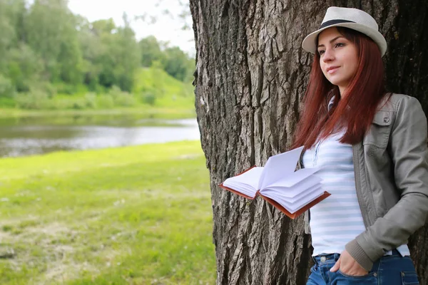 Tyttö kirjan kanssa puistossa — kuvapankkivalokuva