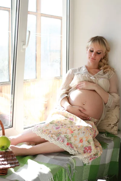 怀孕的女人坐在窗户旁边 — 图库照片
