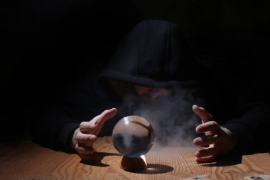 adam siyah başlıklı cristal topu ile