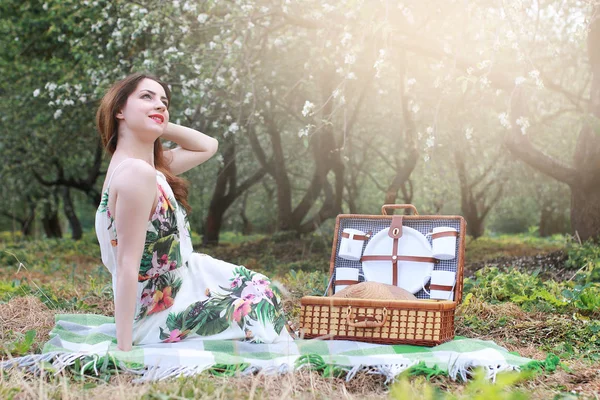 Dívka na pikniku v jablečném sadu s košíkem výrobků — Stock fotografie