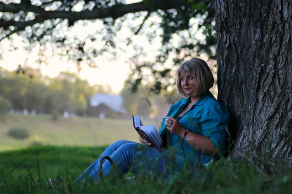 Vrouw in de park boom lezen boek — Stockfoto