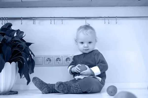 Zwart-wit foto van het kindje in de keuken zit op een tafel — Stockfoto