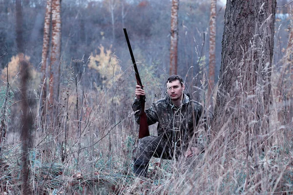 Ένας άνδρας στο καμουφλάζ και με ένα τουφέκι κυνήγι σε ένα δάσος για ένα sp — Φωτογραφία Αρχείου
